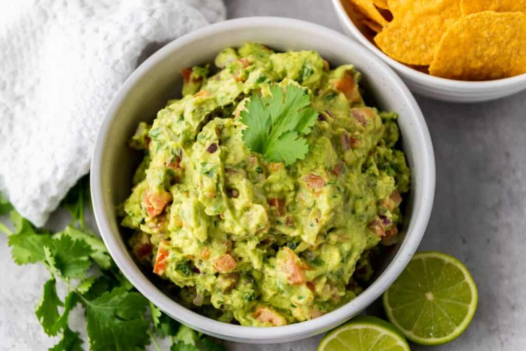 Close up of white bowl of green guacamole.