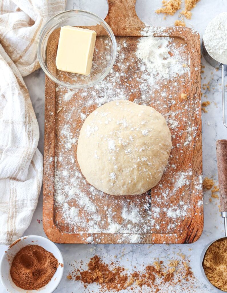 Overhead view of a ball of bread dough on wooden floured surface.