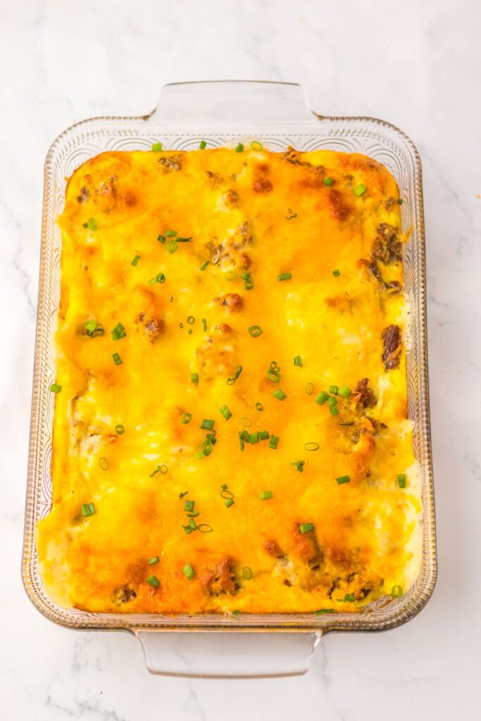 Overhead view of cooked casserole topped with melted cheese in glass casserole dish.