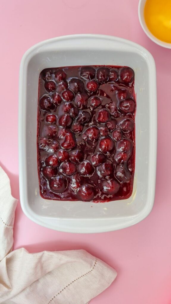 Overhead view of white rectangular baking dish with cherry pie filling on the bottom.