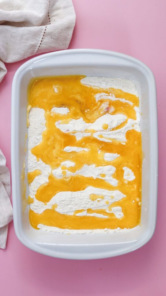 Overhead view of white rectangular baking dish with white powder topped with melted butter in a zig-zag pattern.