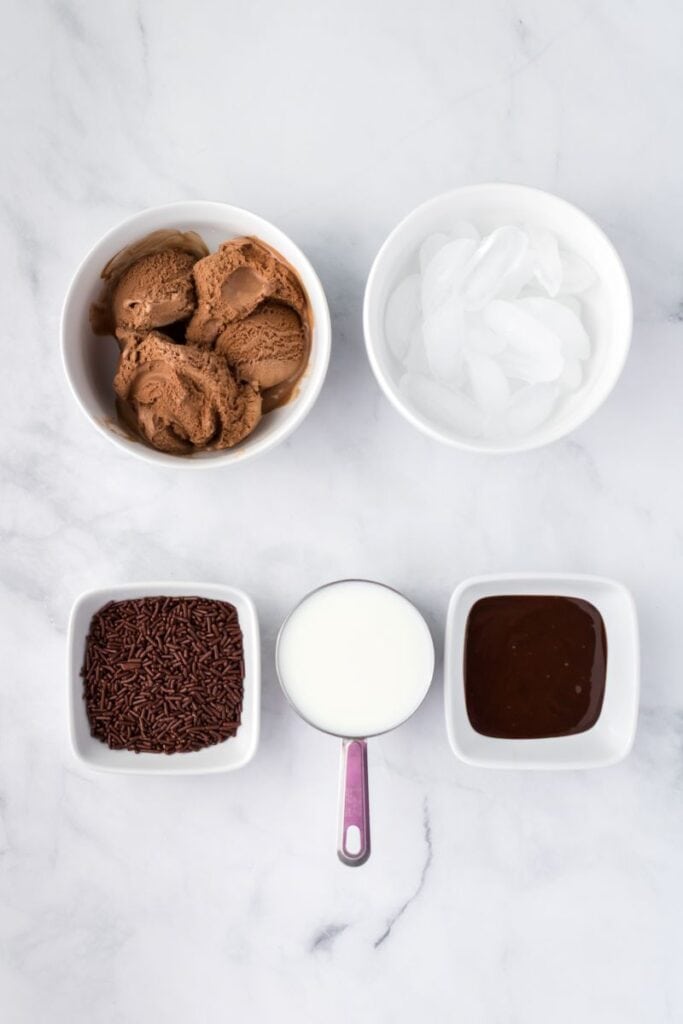 Overhead view of chocolate milkshake ingredients in white bowls.