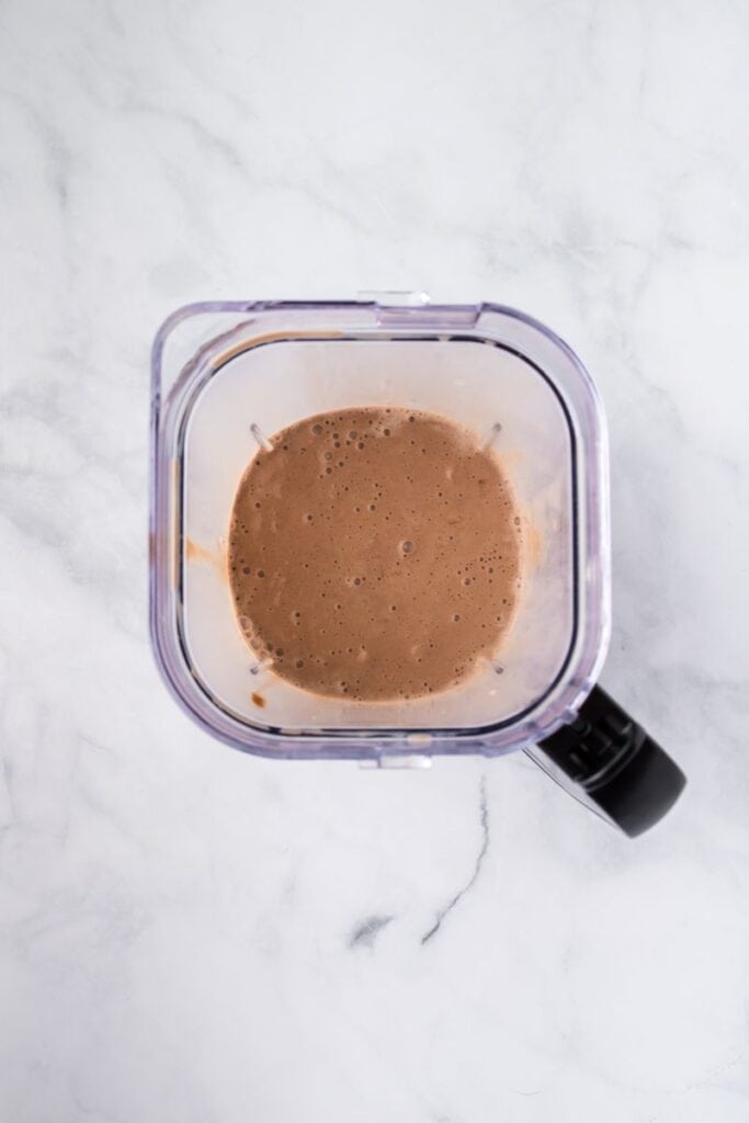 Overhead view of chocolate milkshake in clear blender cup.