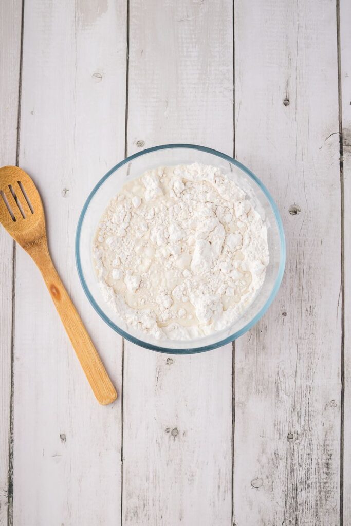 Overhead view of glass bowl with flour and milk.