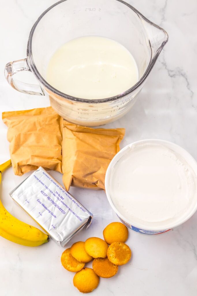 Ingredients for banana pudding cake on white surface.