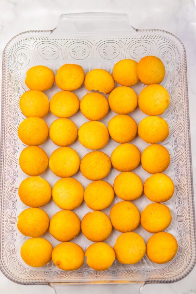 Vanilla wafer cookies lining the bottom of clear glass rectangular dish.