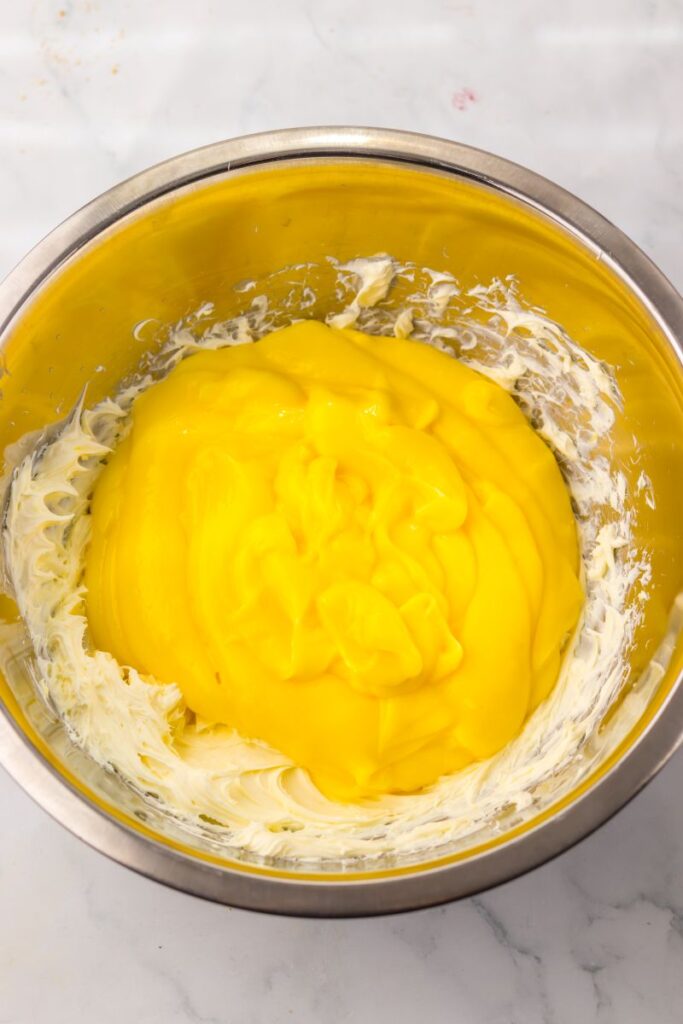 Thick yellow mixture on top of whipped cream cheese in silver bowl.