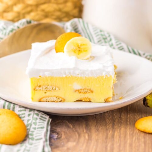 Side view of one slice of banana pudding cake on white plate.