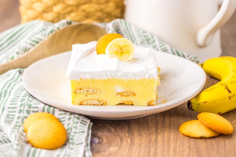 Side view of one slice of banana pudding cake on white plate.