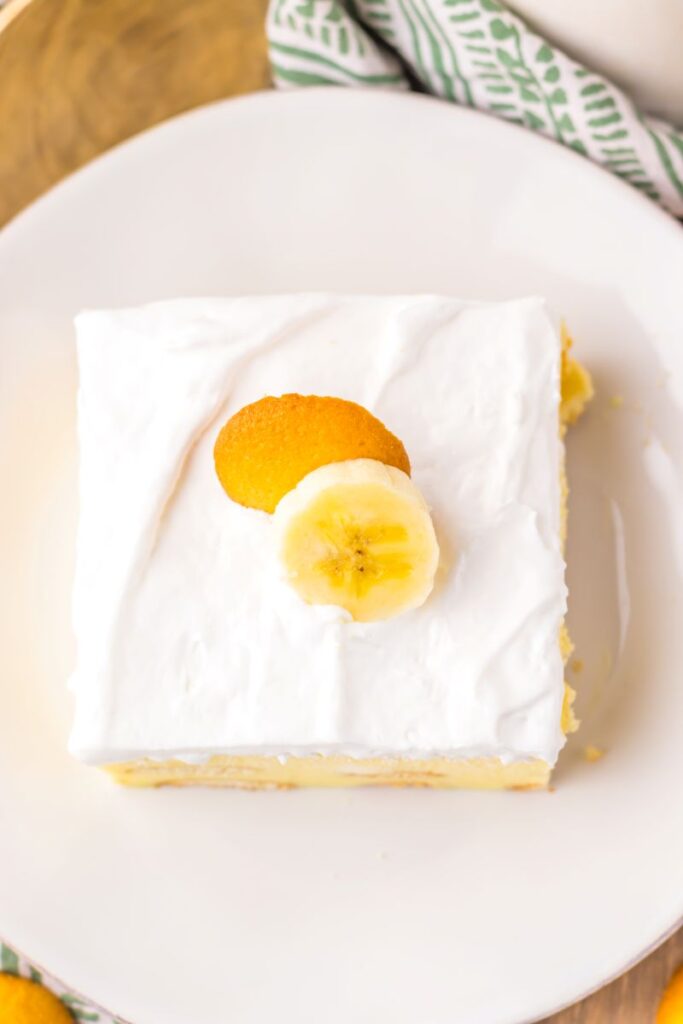 Overhead view of one slice of banana pudding cake on white plate.