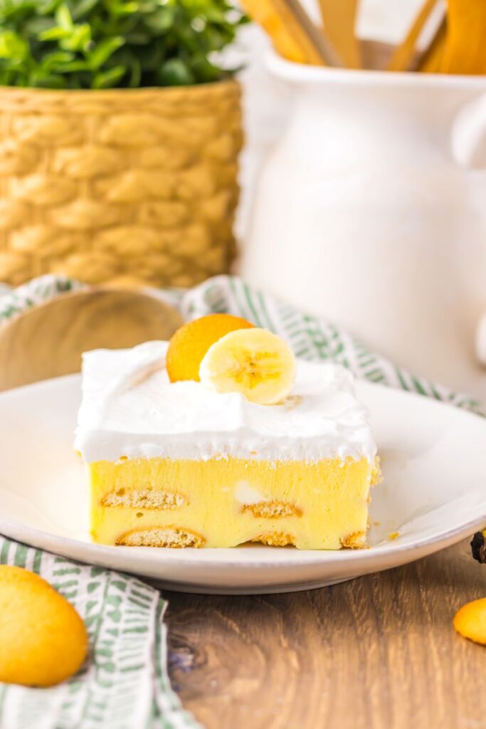 Side view of one slice of banana pudding cake on white plate.