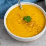 Closeup view of two white bowls with orange soup.
