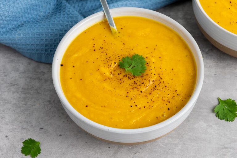 Closeup view of two white bowls with orange soup.