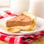 Side view of chocolate peanut butter pie on white plate.