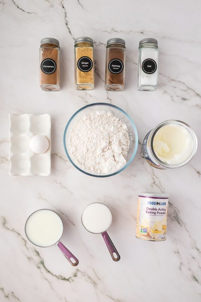 Ingredients for spice muffins in bowls on white background.
