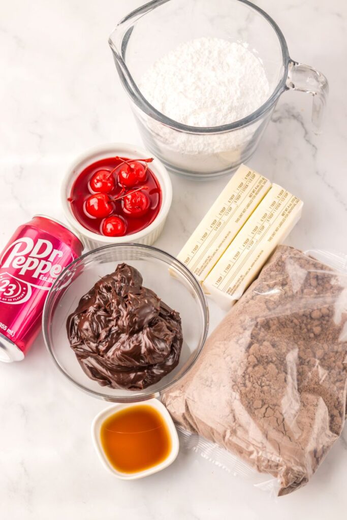 Overhead view of ingredients for Dr Pepper cake on white surface.