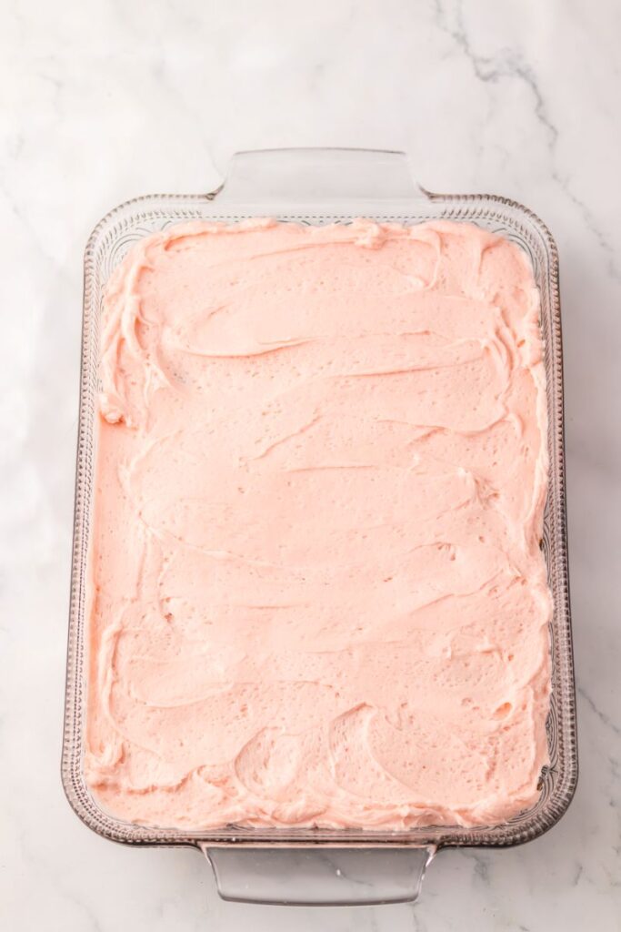 Overhead view of rectangular cake with pink frosting.