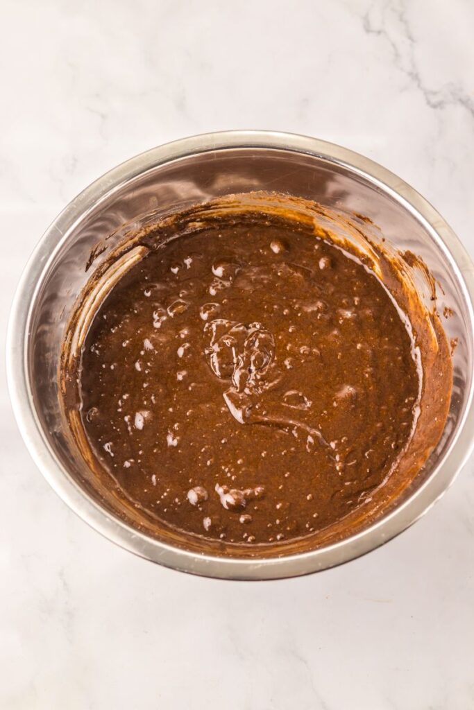 Overhead view of chocolate cake batter in silver bowl.