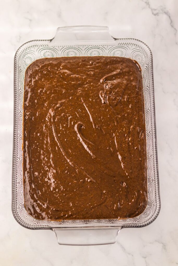 Overhead view of chocolate cake batter in rectangular glass dish.