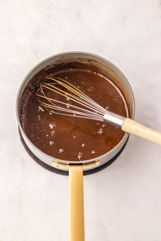 Round pot with hot fudge and whisk.