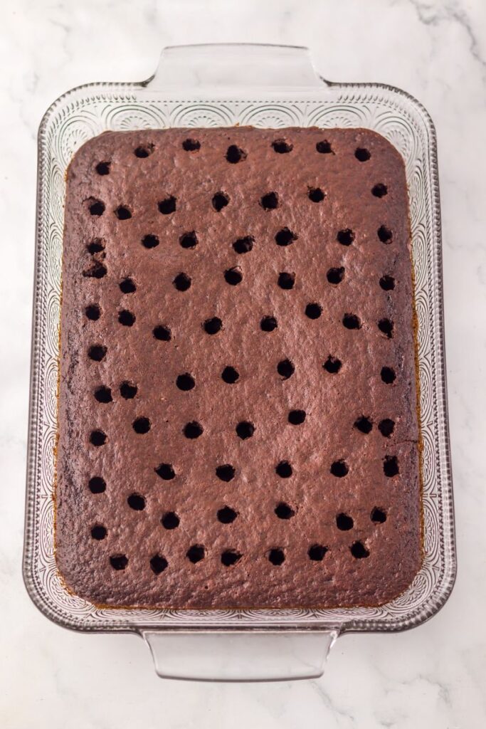 Overhead view of rectangular chocolate cake with holes poke in.