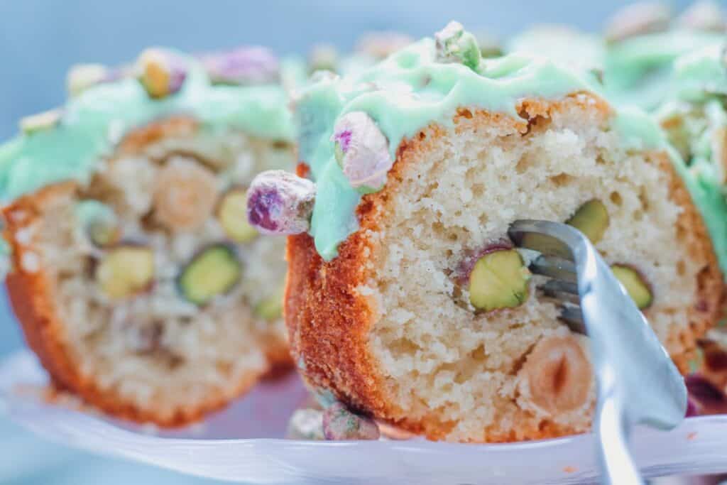Side view of pistachio bundt cake with fork through it.