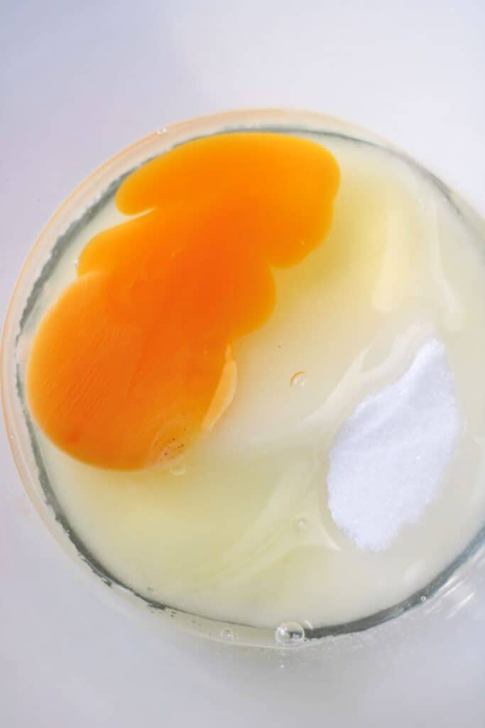 Clear bowl with eggs and sugar.