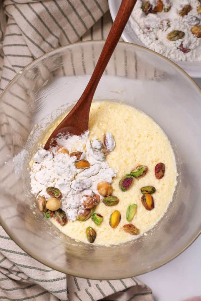 Overhead view of thick yellow liquid with white powder and pistachios.