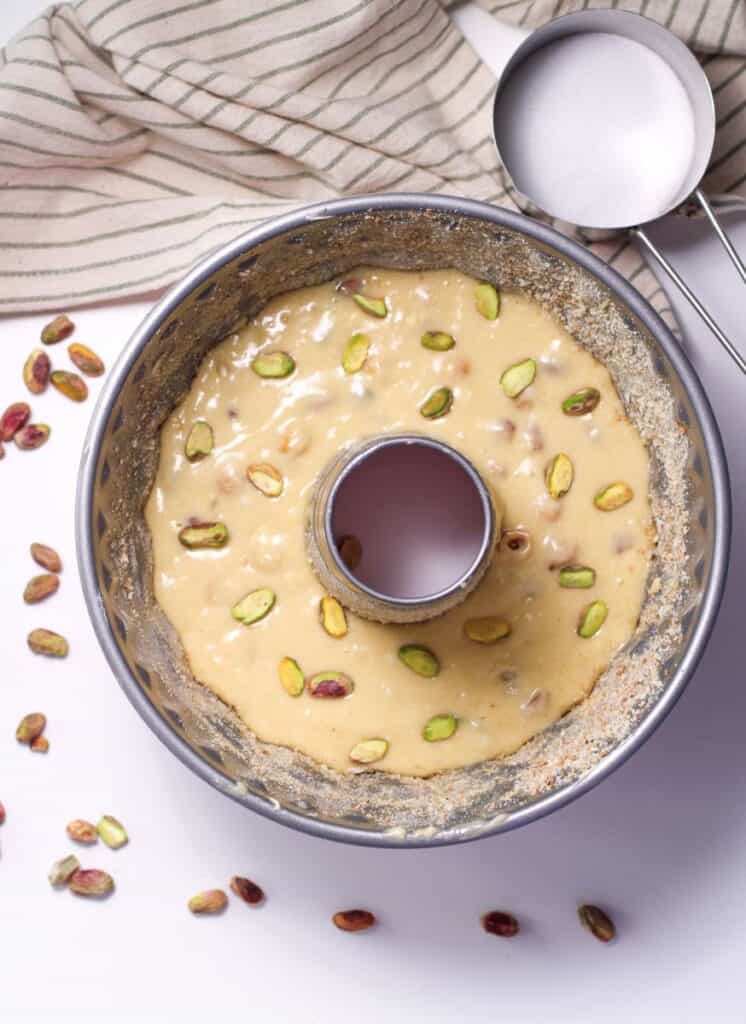 Overhead view of cake batter with pistachios in Bundt cake pan.
