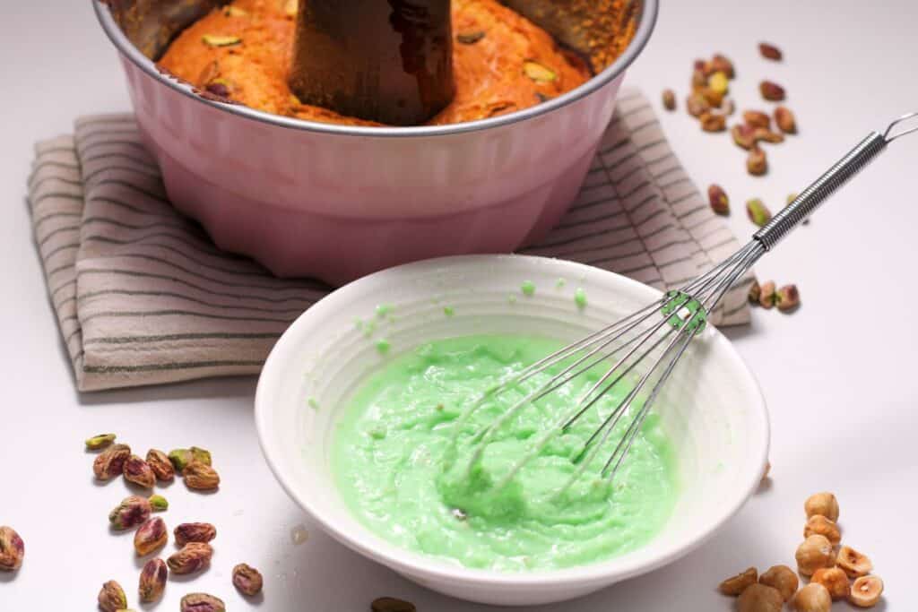 White bowl of green glaze with whisk.