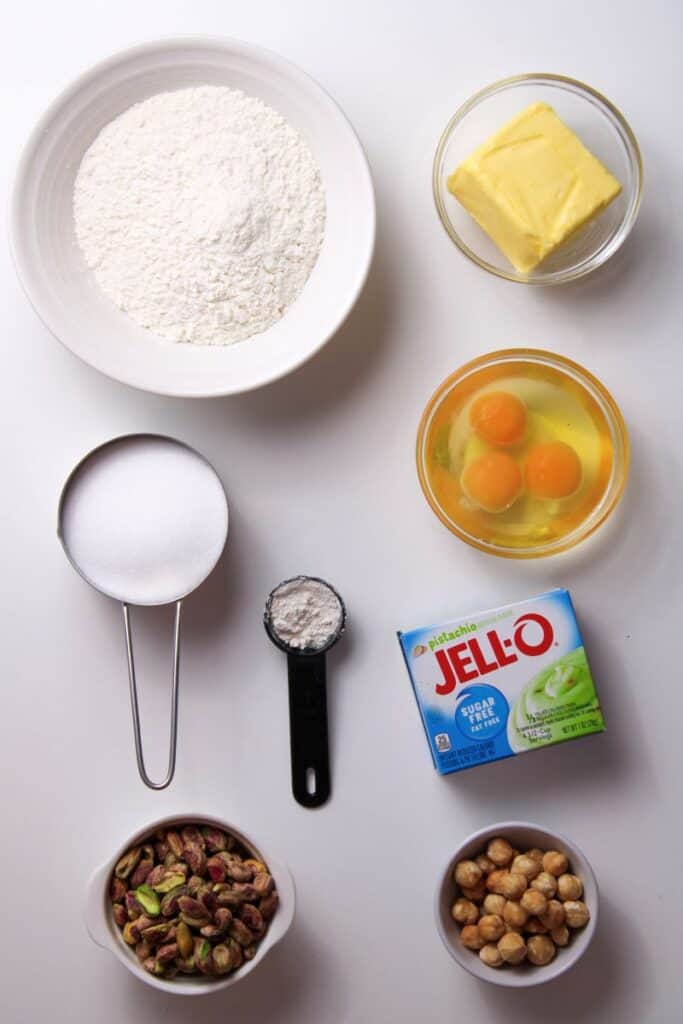 Ingredients for pistachio bundt cake in bowls on white background.