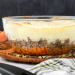 Side view of clear bowl layered with carrots, ground beef, and mashed potatoes.