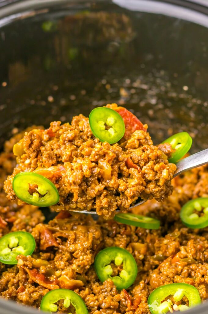 Close up of spoon containing ground beef and sliced jalapenos.