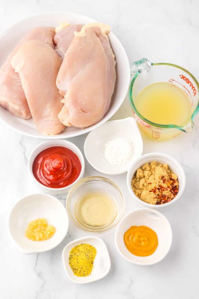 Ingredients for lemonade chicken in white bowls on marble background.