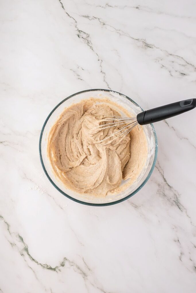 Overhead view of batter in clear bowl with whisk.