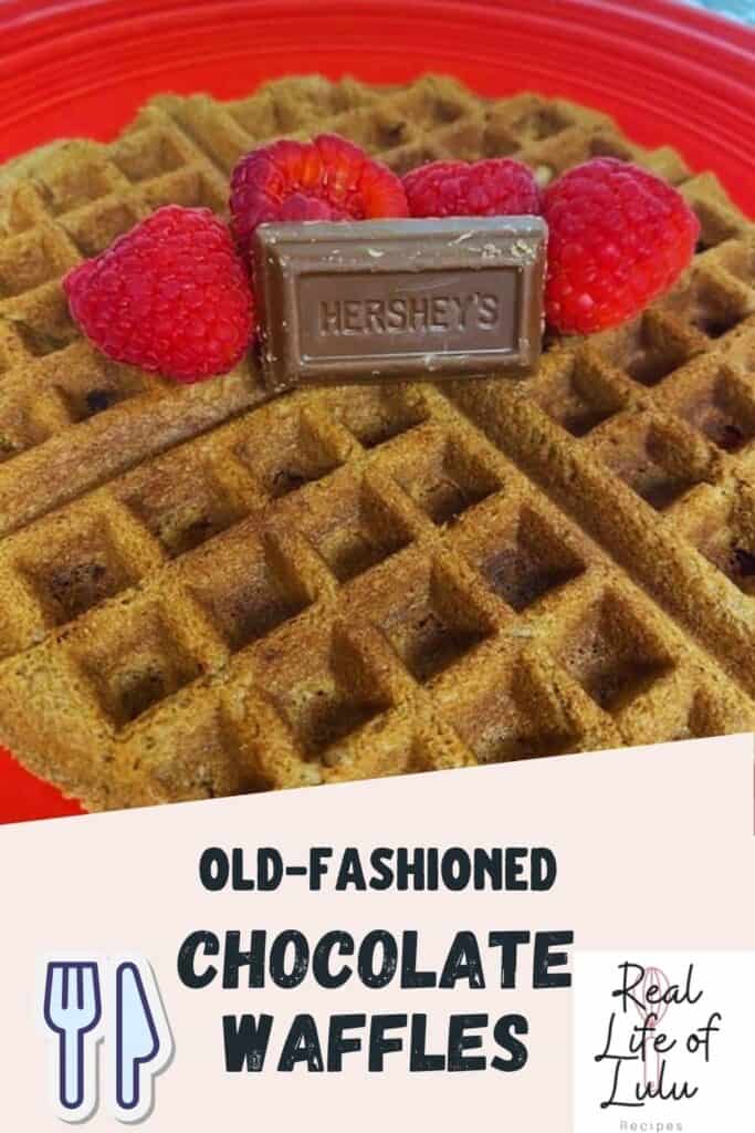 A round chocolate waffle on a red plate, topped with fresh raspberries and a piece of Hershey’s chocolate. Text reads “Old-Fashioned Chocolate Waffles, Real Life of Lulu Recipes.”.