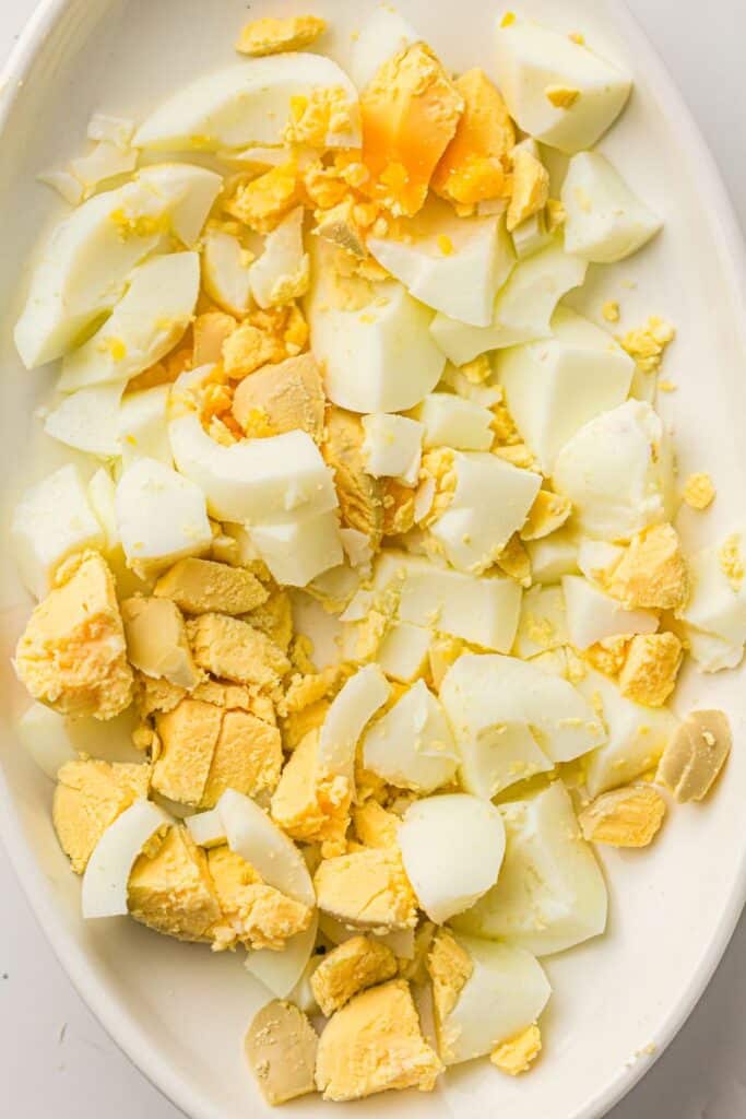 Chopped hard-boiled eggs with yellow yolks and white egg whites on a white plate.