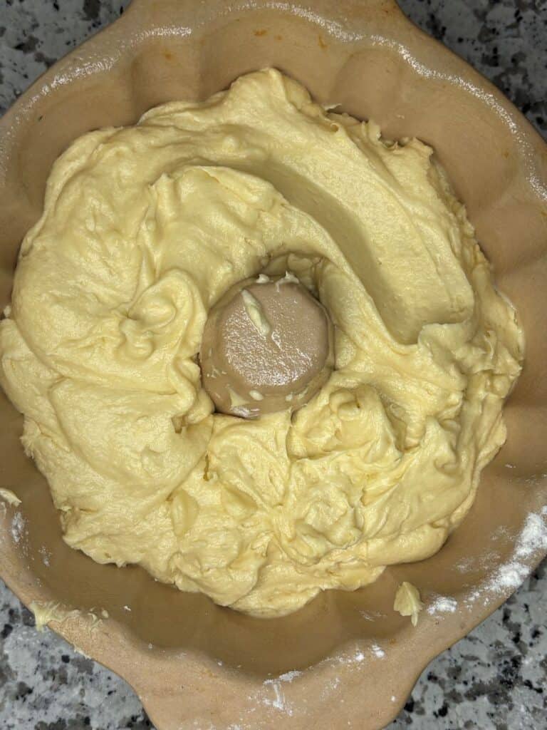 Cake batter spread evenly in a fluted bundt pan, ready for baking, with a creamy, pale yellow color and smooth texture.