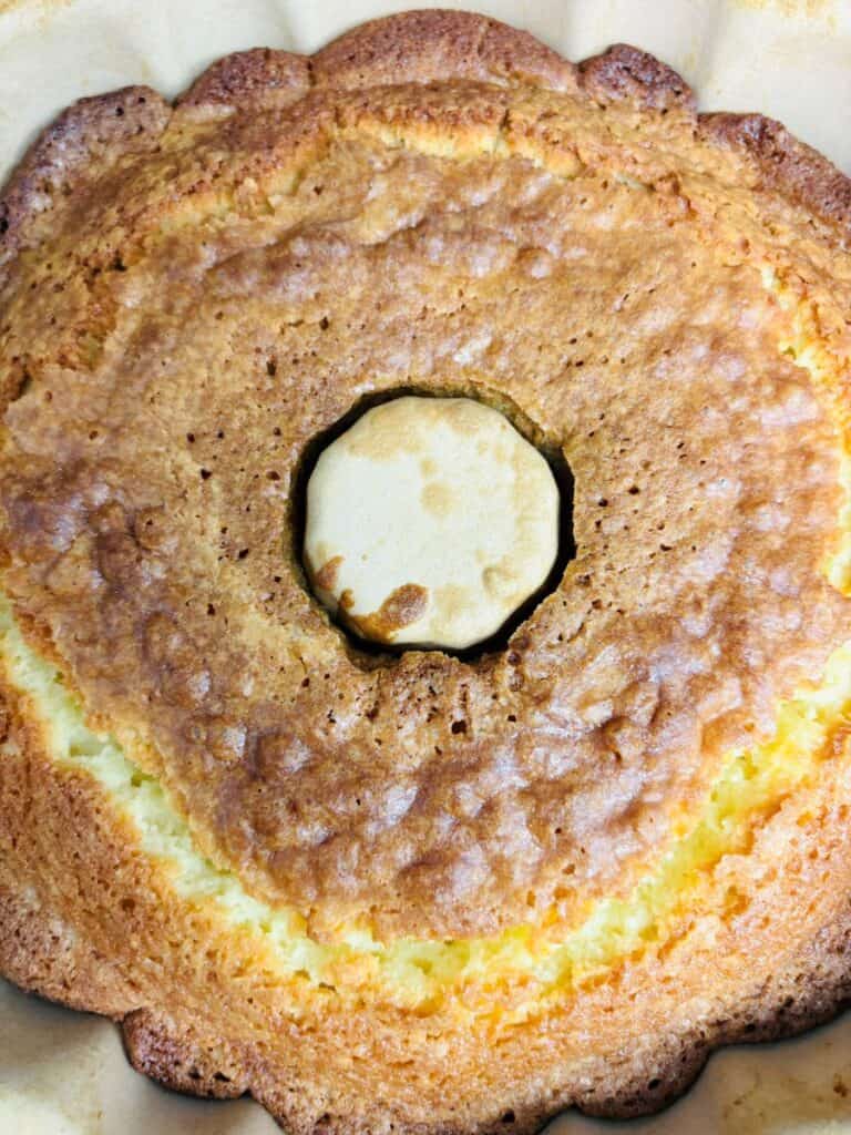A close-up of a golden-brown bundt cake with a crisp top, baked in a fluted pan, showing the cakes texture and central hole.