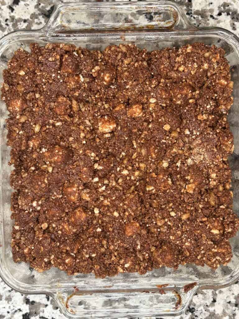 A glass baking dish filled with a baked chocolate oat dessert, possibly brownies or a crumble, resting on a speckled granite countertop.