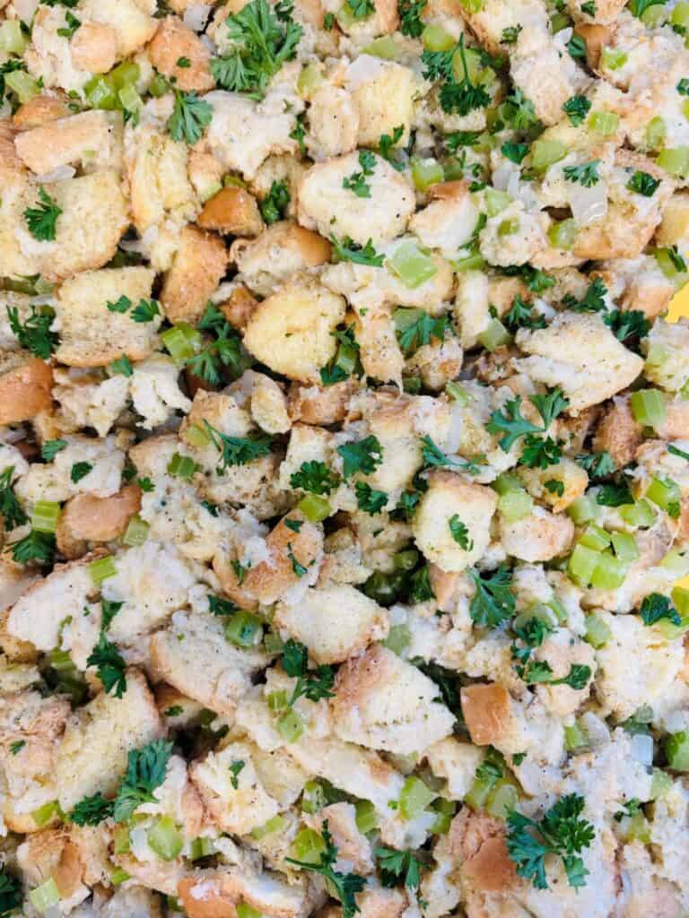 Close-up of traditional bread stuffing with chunks of bread, diced celery, onions, and fresh parsley mixed together.