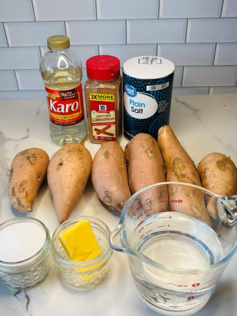 Ingredients for a recipe: Karo light corn syrup, ground cinnamon, salt, six sweet potatoes, a small bowl of sugar, a pat of butter, and a measuring cup of water.