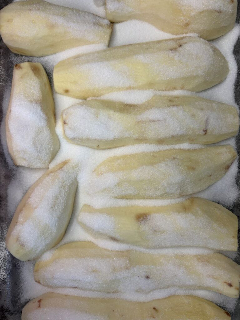 Peeled sweet potatoes coated in granulated sugar.