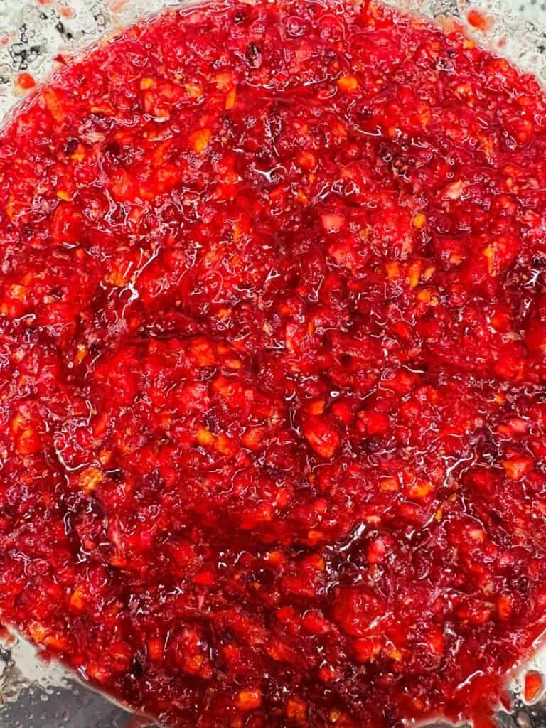 A bowl filled with chunky, bright red cranberry relish.