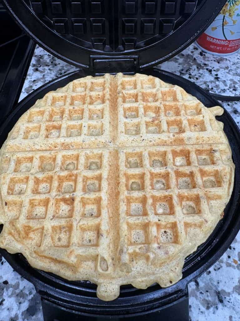 A golden-brown waffle cooked in a round waffle iron.