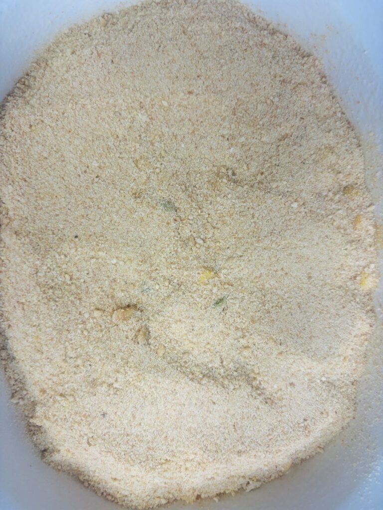 A container filled with fine, light-tan dry crumbs.